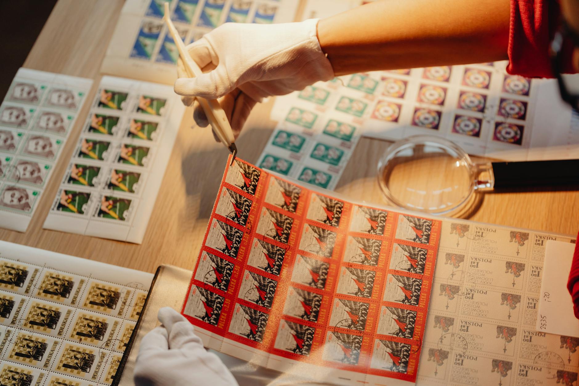A person wearing white cotton inspection gloves gently turning over a heavy, ornate antique silver teapot to reveal a cluster of small hallmarks on the base. - Antique identification guide