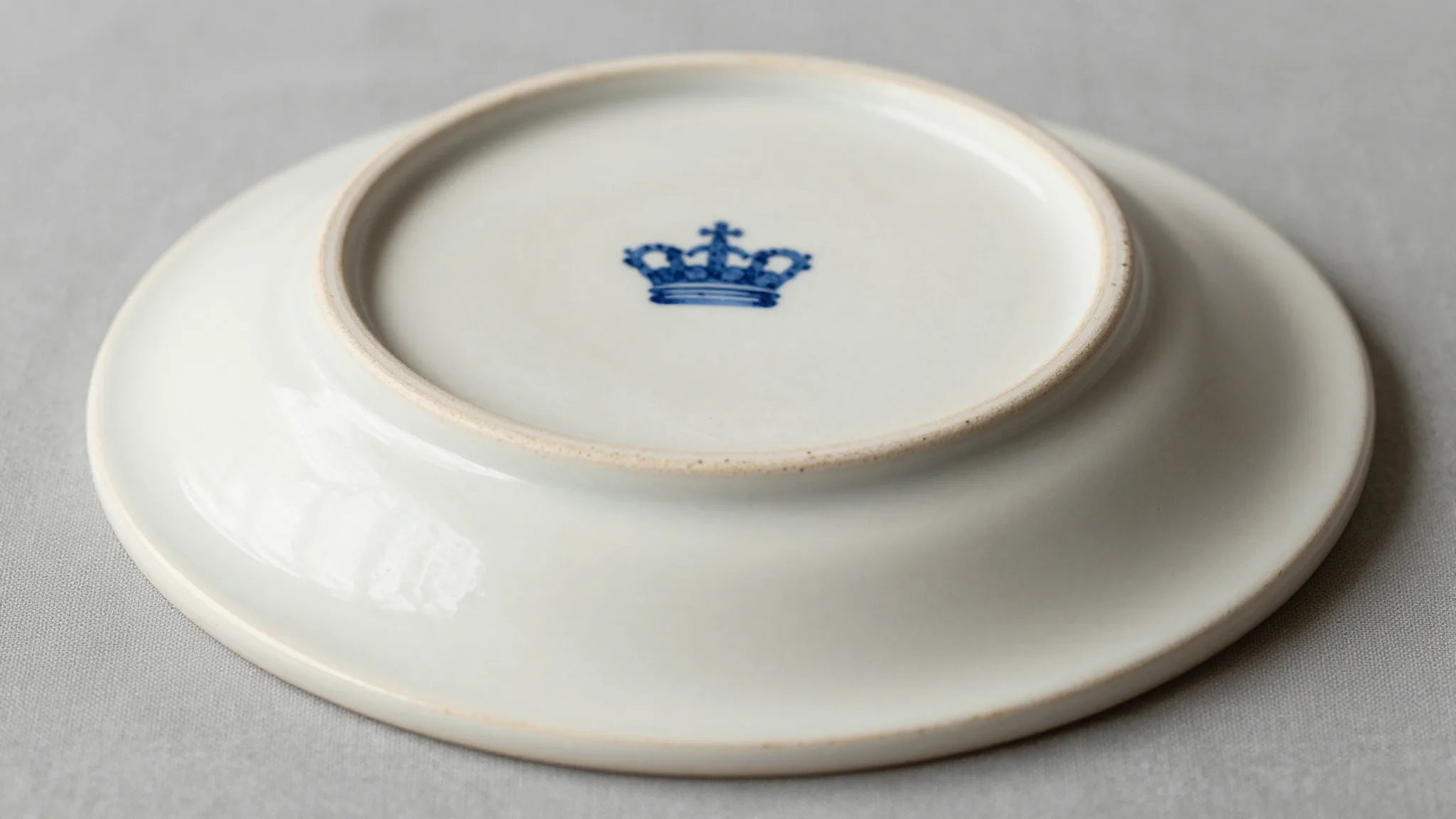 Close-up of antique pottery base showing impressed maker's mark and painted backstamp on cream earthenware